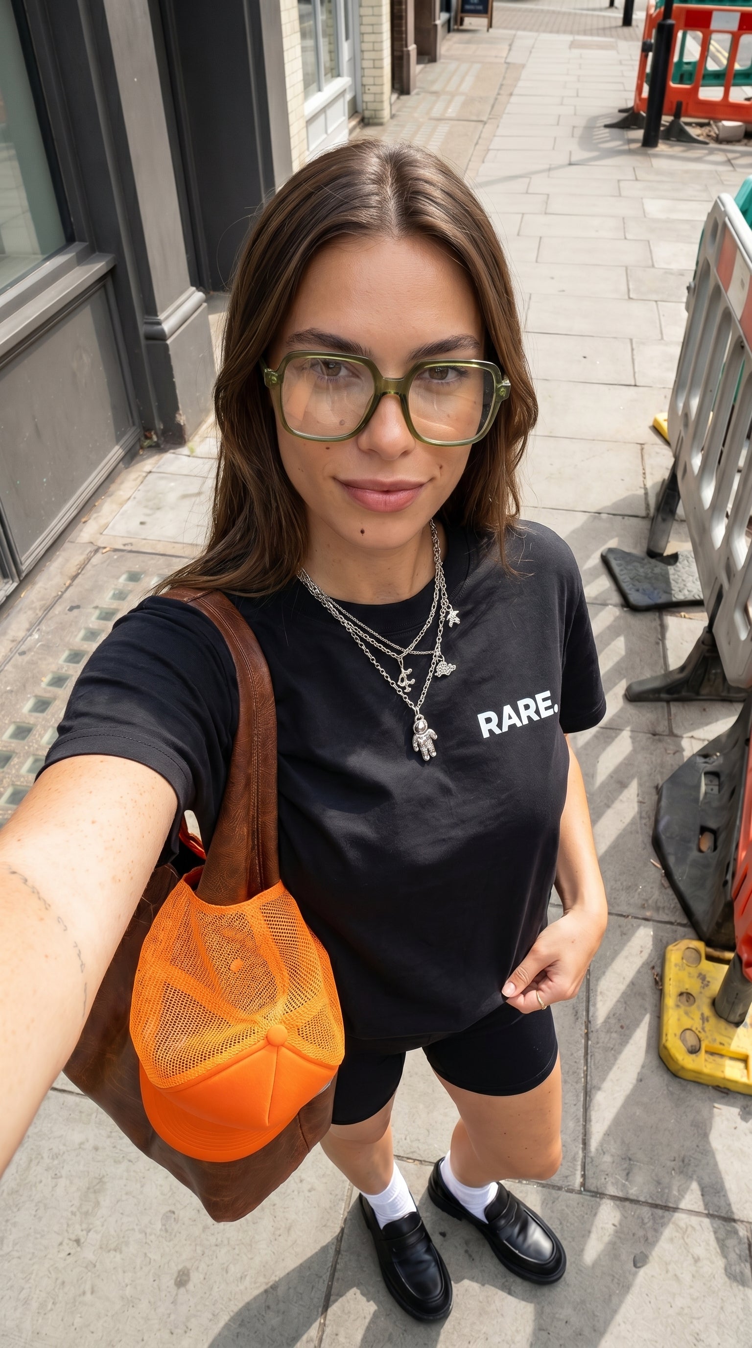 Person wearing a black 'RARE' t-shirt on a city street.